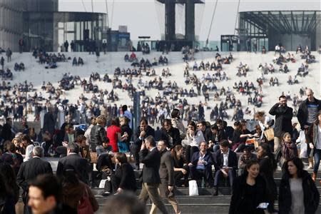 Businessmen enjoy the good weather at lunch time on the steps in front of the Arche de la Defense, in the financial and business district west of Paris, as warm and sunny weather continues in France, March 13, 2014. REUTERS/Charles Platiau