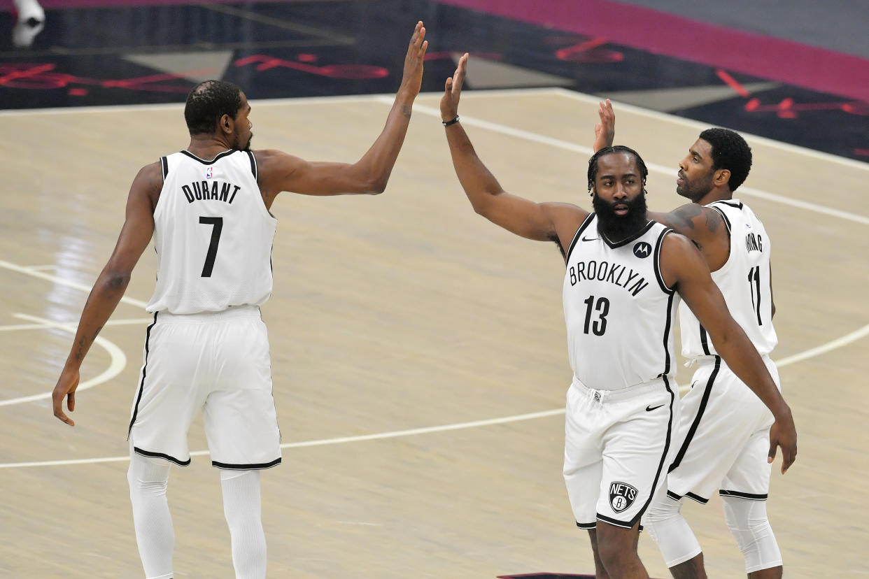 CLEVELAND, OHIO - JANUARY 20: Kevin Durant #7  James Harden #13 and Kyrie Irving #11 of the Brooklyn Nets celebrate during the first quarter against the Cleveland Cavaliers at Rocket Mortgage Fieldhouse on January 20, 2021 in Cleveland, Ohio. NOTE TO USER: User expressly acknowledges and agrees that, by downloading and/or using this photograph, user is consenting to the terms and conditions of the Getty Images License Agreement. (Photo by Jason Miller/Getty Images)