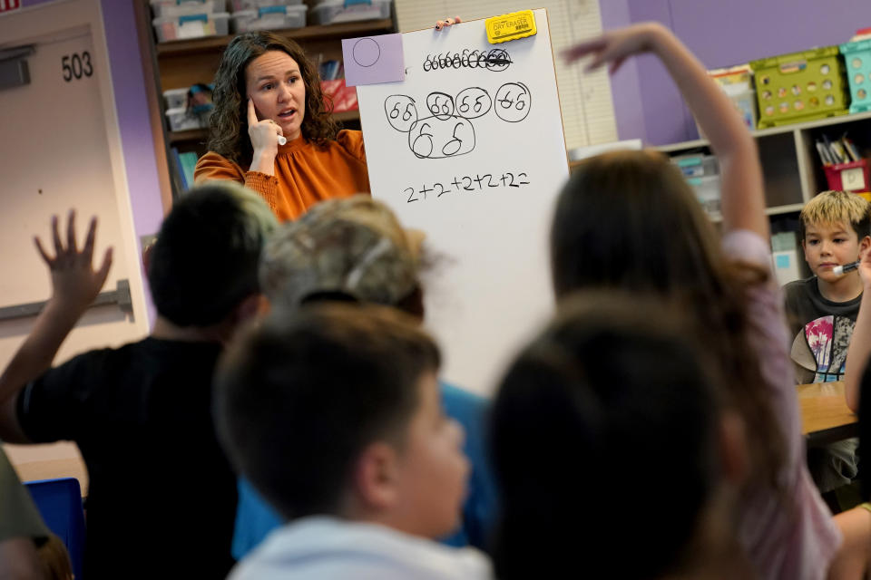 Whittier Elementary School teacher Kayla Cowen interacts with students, Tuesday, Oct. 18, 2022 in Mesa, Ariz. Like many school districts across the country, Mesa has a teacher shortage due in part due to low morale and declining interest in the profession. Five years ago, Mesa allowed Whittier to participate in a program making it easier for the district to fill staffing gaps, grant educators greater agency over their work and make teaching a more attractive career. The model, known as team teaching, allows teachers to combine classes and grades rotating between big group instruction, one-on-one interventions, small study groups or whatever the team agrees is a priority each day. (AP Photo/Matt York)
