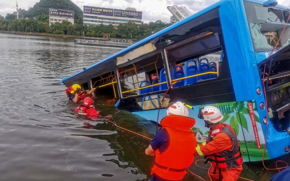 Rescue workers attend the scene where the bus crashed into a lake - STR/AFP via Getty Images