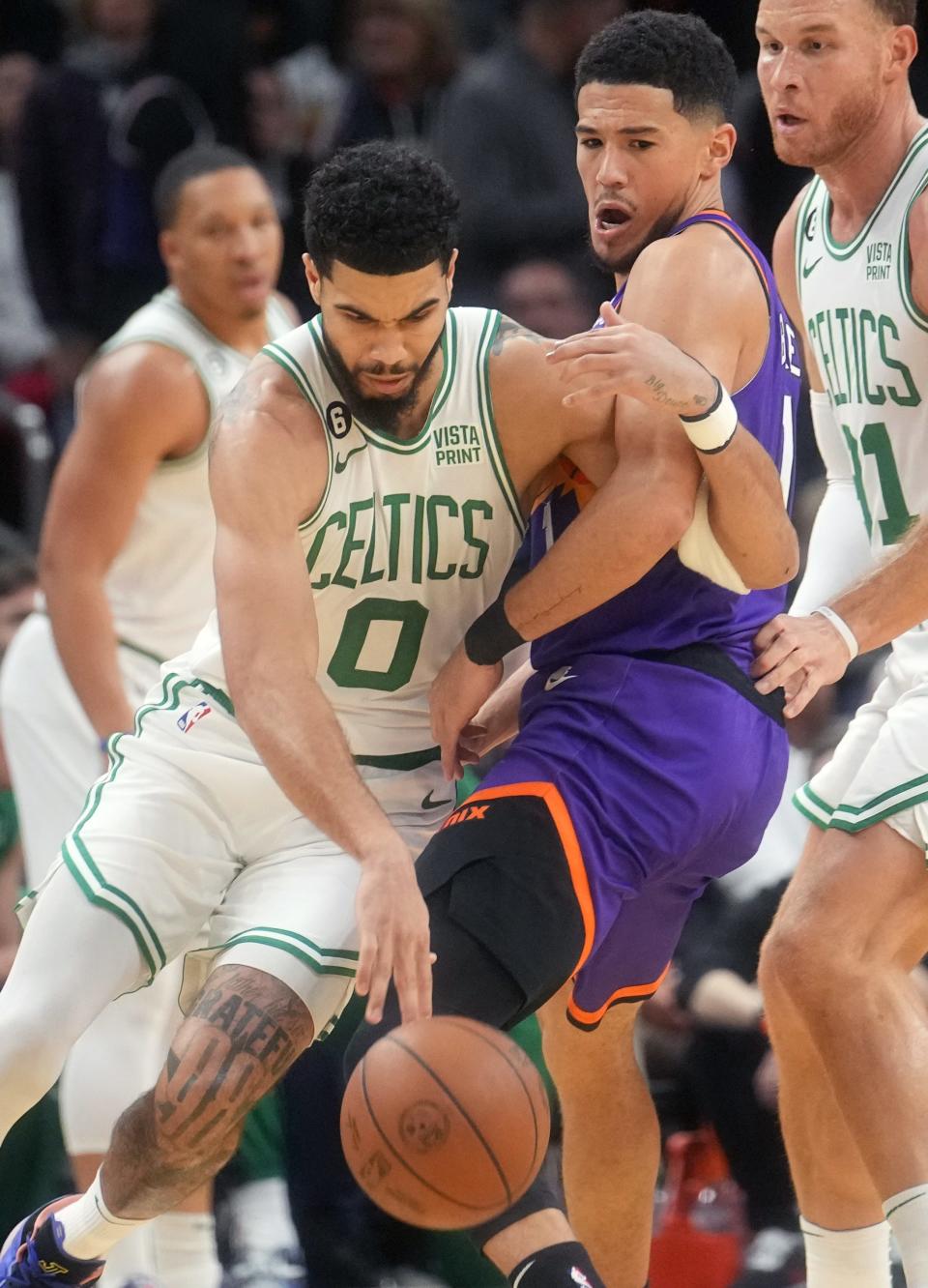 Dec 7, 2022; Phoenix, Arizona, USA; Boston Celtics forward 	Jayson Tatum (0) drives past Phoenix Suns guard Devin Booker (1) at Footprint Center.