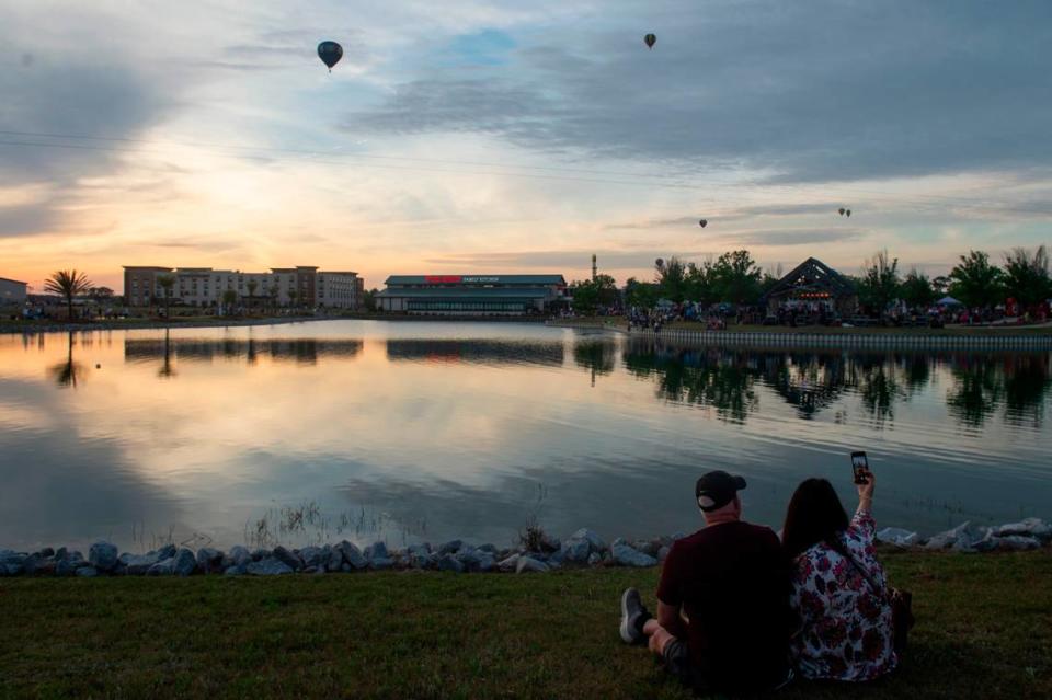 A couple takes a selfie as hot air balloons fly by during the Gulf Coast Hot Air Balloon Festival at OWA in Foley, Alabama on Thursday, May 4, 2023.