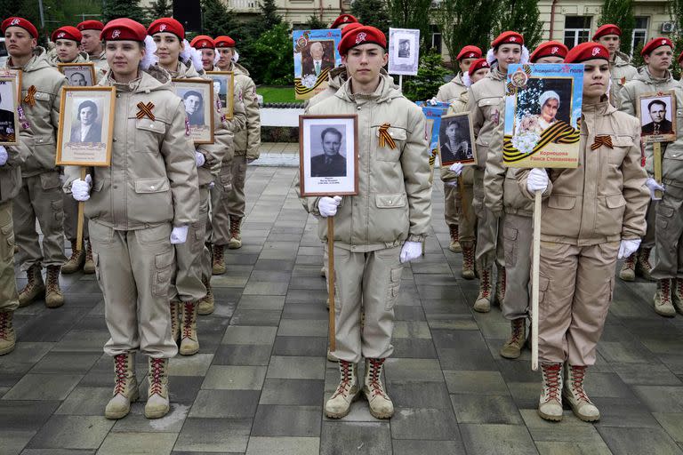 Miembros del movimiento de la Juventud Patriótica Rusa Yunarmiya sostienen retratos de soldados de la Segunda Guerra Mundial mientras participan en el acto del Régimen Inmortal durante el desfile del Día de la Victoria en Rostov del Don, el 8 de mayo de 2023.