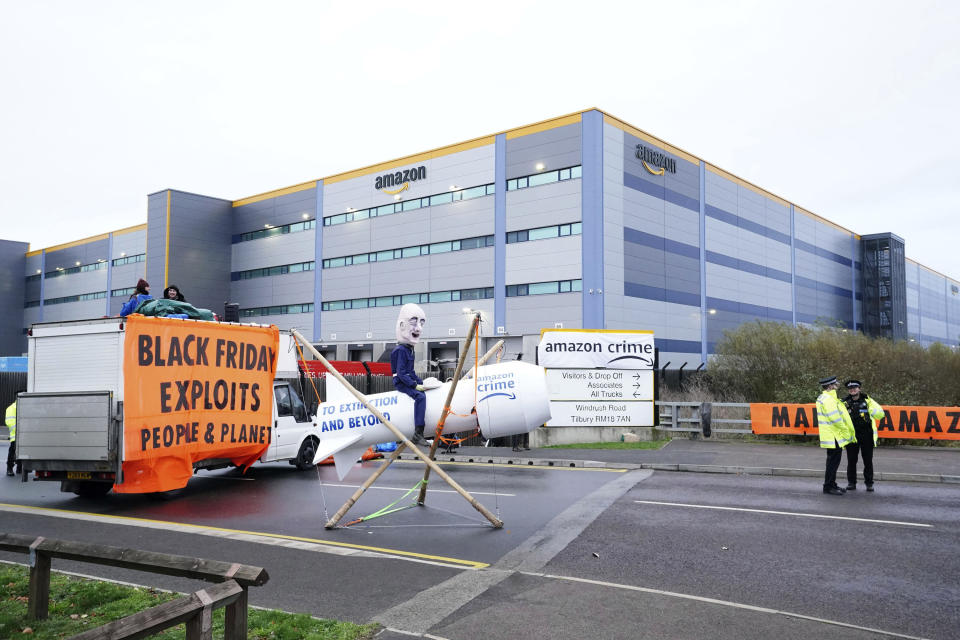 Activists from Extinction Rebellion block the entrance to the Amazon fulfilment centre, preventing lorries from entering or leaving on Black Friday, the global retail giant's busiest day of the year, in Tilbury, England, Friday Nov. 26, 2021. The group has targeted Amazon sites in Doncaster, Darlington, Dunfremline, Newcastle, Manchester, Peterborough, Derby, Coventry, Rugeley, Dartford, Bristol, Tilbury and Milton Keynes. (Ian West/PA via AP)