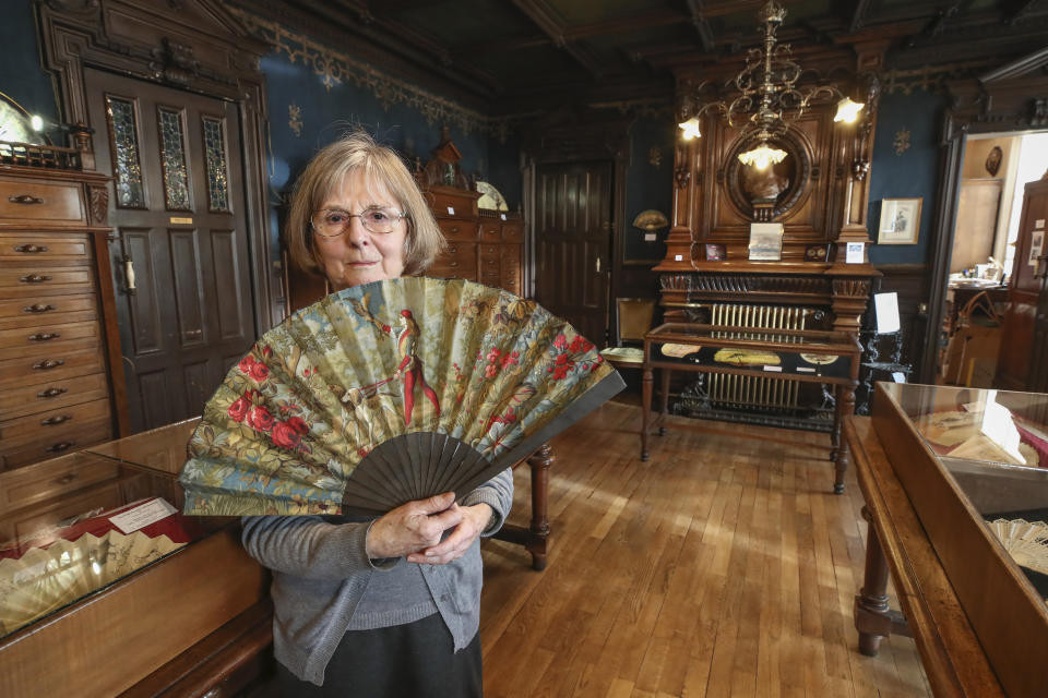 Anne Hoguet, 74, fan maker and director of the hand fan-making museum poses with a a wood roasted hand fan representing the falcon hunt, gouache painting on paper dated from 1880 in Paris, Wednesday, Jan. 20, 2021. The splendid Musee de l'Eventail in Paris, a classed historical monument, is the culture world's latest coronavirus victim. (AP Photo/Michel Euler)