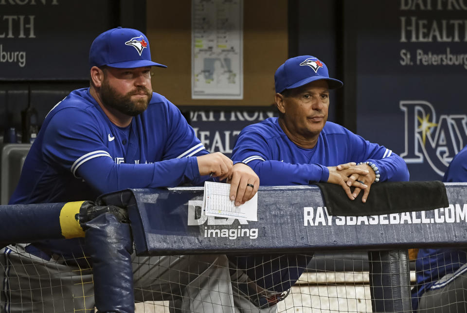 Toronto Blue Jays coach John Schneider, left, and manager Charlie Montoyo watch from the dugout during the eighth inning of a baseball game against the Tampa Bay Rays, Saturday, July 10, 2021, in St. Petersburg, Fla.(AP Photo/Steve Nesius)