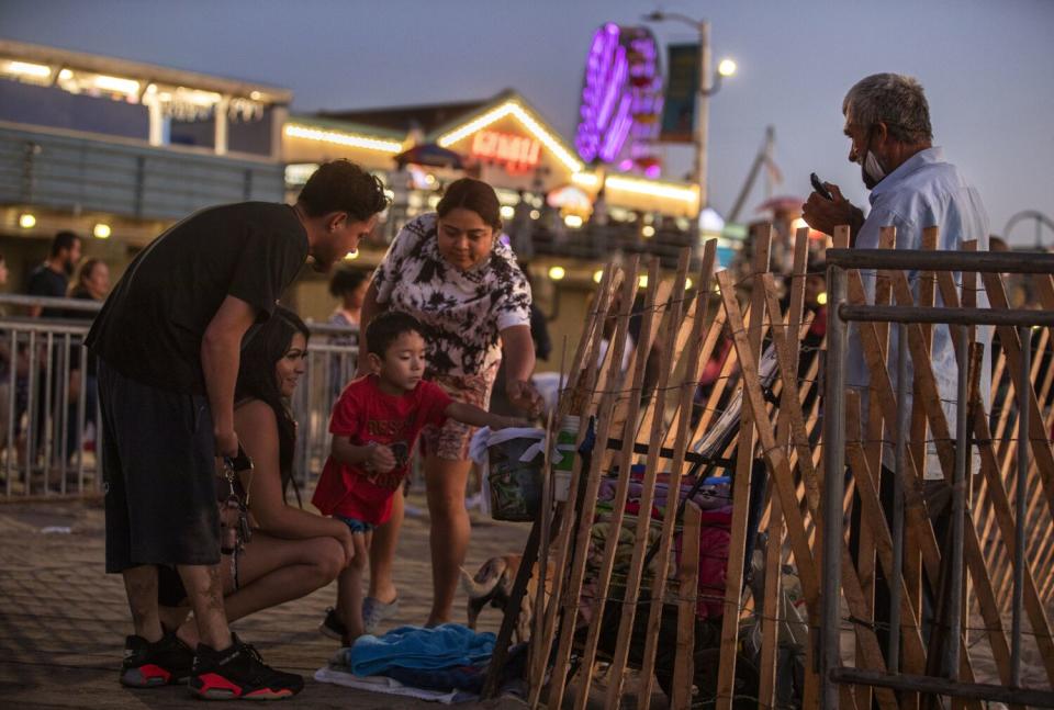 A boy puts money into the tip container with a little help from his mother as Augustine Hurtado plays the harmonica.