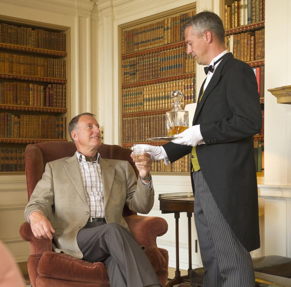 butler handing a drink to man