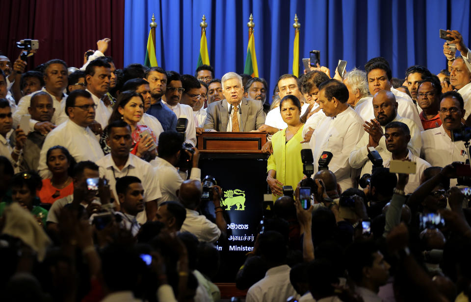 In this Sunday, Dec. 16, 2018, file photo, Sri Lanka's reinstated Prime Minister Ranil Wickeremesinghe, center, surrounded by his loyal lawmakers and supporters speaks after assuming duties in Colombo, Sri Lanka. Sri Lanka's president has reappointed Ranil Wickremesinghe as prime minister, nearly two months after firing him and setting off weeks of political stalemate. (AP Photo/Eranga Jayawardena, File)