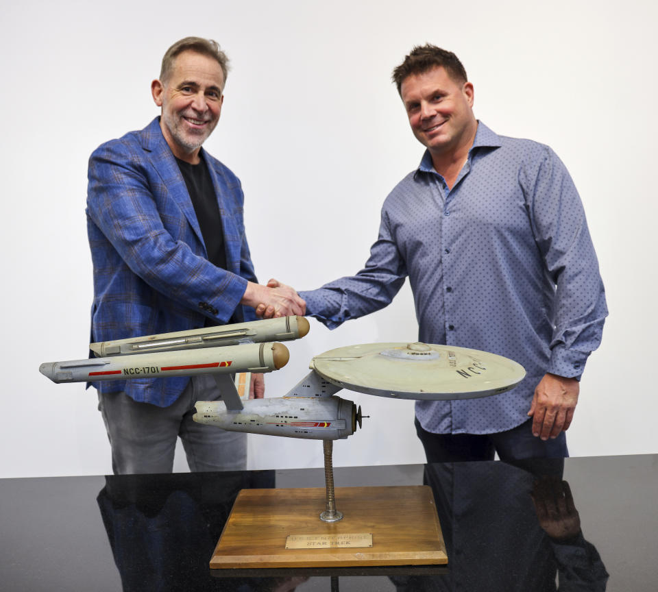 Joe Maddalena, executive vice president of Heritage Auctions, left, and Eugene “Rod” Roddenberry, the son of “Star Trek” creator Gene Roddenberry, shake hands over the recently recovered first model of the USS Enterprise at the Heritage Auctions in Los Angeles, April 13, 2024. The model — used in the original “Star Trek” television series — has been returned to Eugene, decades after it went missing in the 1970s. (Josh David Jordan/Heritage Auctions via AP)