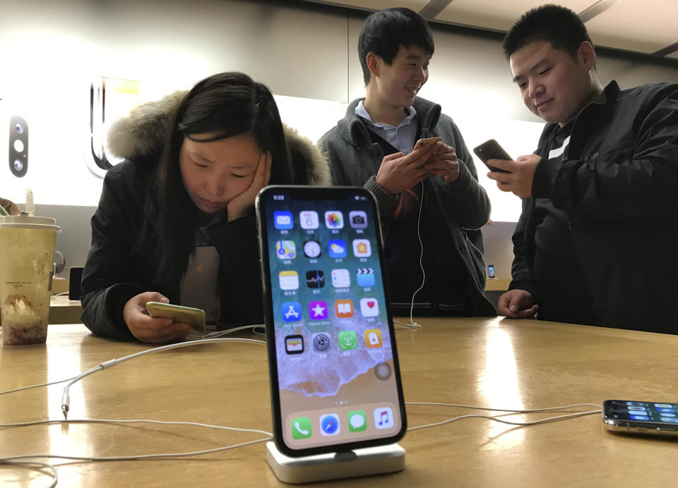 FILE - In this Nov. 6, 2017, file photo, shoppers check out the iPhone X at an Apple store in Beijing, China. U.S. chipmaker Qualcomm says it’s won an order in a Chinese court banning some Apple phones in China as part of a long-running dispute over patents. Qualcomm said Monday, Dec. 10, 2018, that the Fuzhou Intermediate People’s Court in China has granted preliminary injunctions ordering four Chinese subsidiaries of Apple to stop selling and importing iPhones 6S through X. (AP Photo/Ng Han Guan, File)