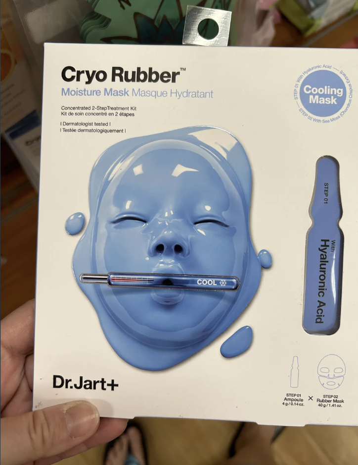 Hand holding Dr. Jart+ Cryo Rubber Moisture Mask box featuring a blue mask with a cooling effect and hyaluronic acid