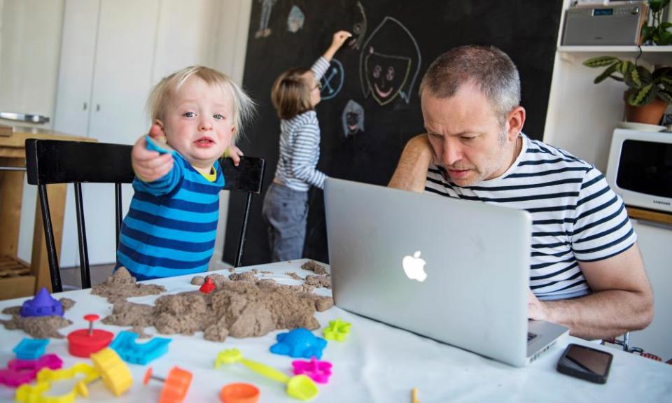 Man trying to work at a laptop surrounded by small children