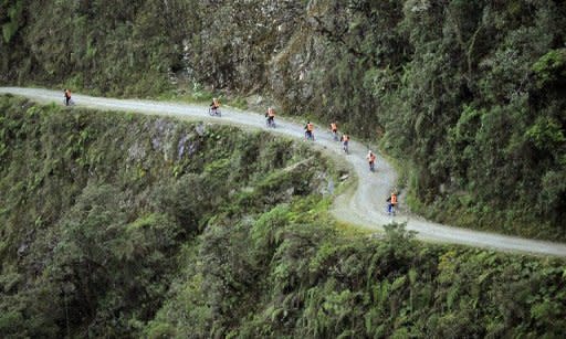Amantes del ciclismo y turistas extranjeros que llegan a Bolivia en busca de aventura extrema suben hasta "la cumbre", a unos 25 kilómetros de La Paz, para lanzarse en bicicleta por la llamada "ruta de la muerte". (AFP | Aizar Raldés)