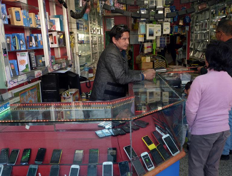 A Bhutanese cell phone vendor speaks with potential customers at a shop in the kingdom's capital Thimphu, on February 20, 2014