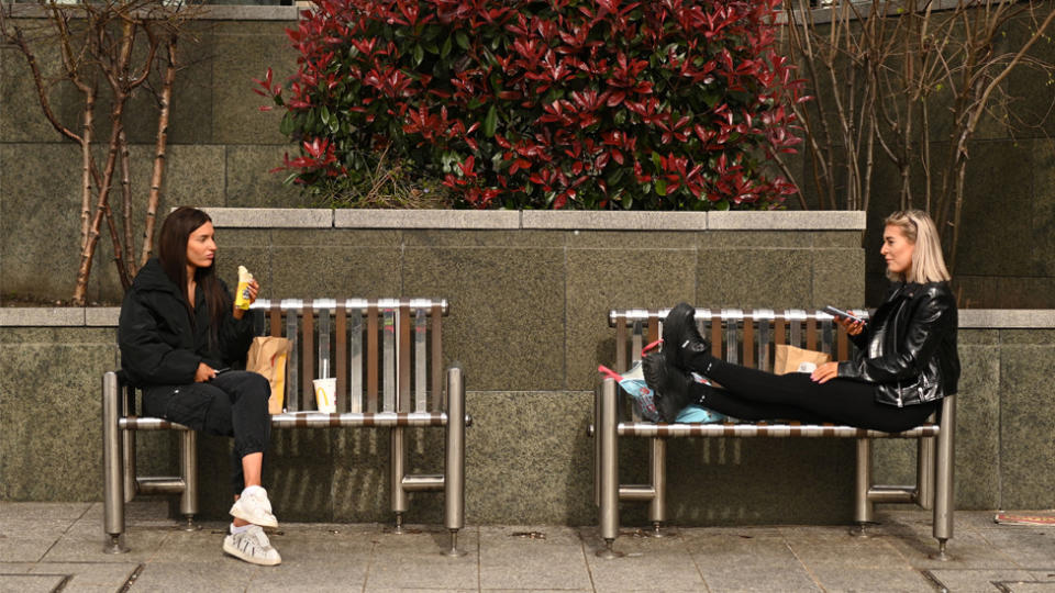 Two women sit apart, as it's revealed social distancing has helped reduce cases of the flu in Australia