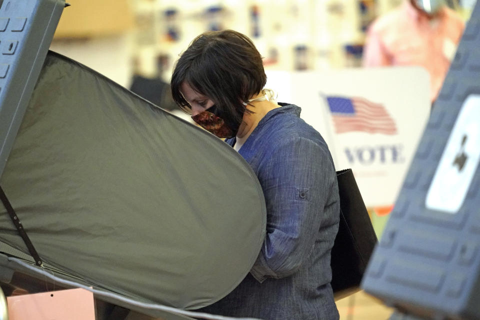 A woman wears a mask while voting, Monday, June 29, 2020, in Houston. Early voting for the Texas primary runoffs began Monday. (AP Photo/David J. Phillip)