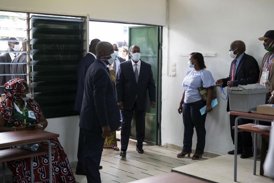 Ivory Coast President Alassane Ouattara, center, arrives to vote at a polling station during presidential elections in Abidjan, Ivory Coast, Saturday, Oct. 31, 2020. Tens of thousands of security forces deployed across Ivory Coast on Saturday as the leading opposition parties boycotted the election, calling President Ouattara's bid for a third term illegal. (AP Photo/Leo Correa)