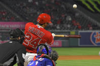 Los Angeles Angels' Kurt Suzuki, center, hits a two-run home run as Texas Rangers catcher Jose Trevino, right, and home plate umpire Brennan Miller watch during the seventh inning of a baseball game Tuesday, April 20, 2021, in Anaheim, Calif. (AP Photo/Mark J. Terrill)