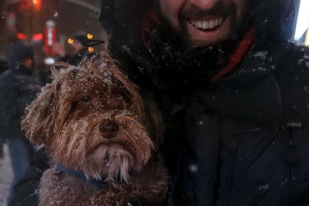 A man holds his dog during a snow storm in Times Square in the Manhattan borough of New York, January 23, 2016. REUTERS/Carlo Allegri