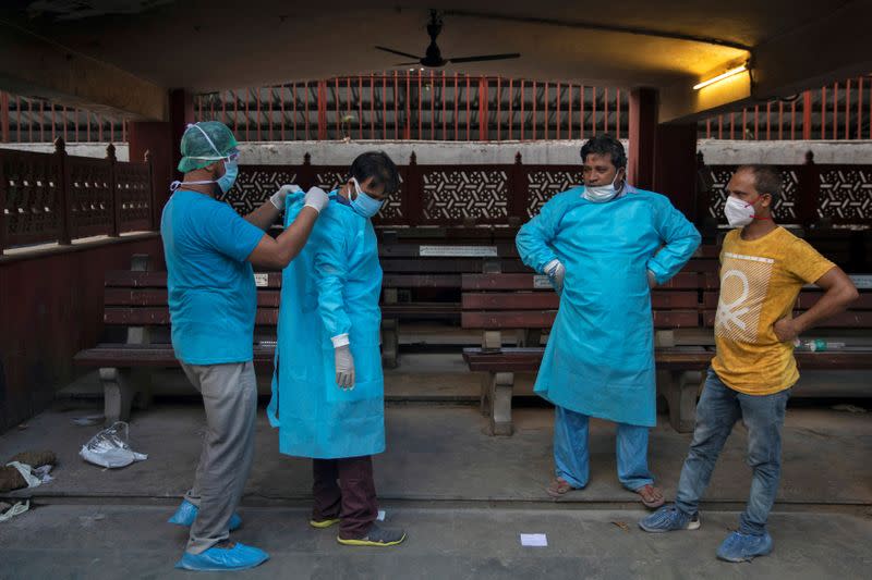 Mohammad Aamir Khan, an ambulance driver, helps a relative of a man who died due to the coronavirus disease, before his cremation at a crematorium in New Delhi