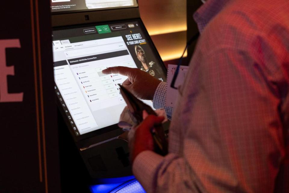 Patrons place bets at a self-service kiosk at Caesars Sportsbook at Red Mile in Lexington on Thursday. There are 14 self-service kiosks for sports wagering at the sportsbook. The facility also offers five manned terminals.