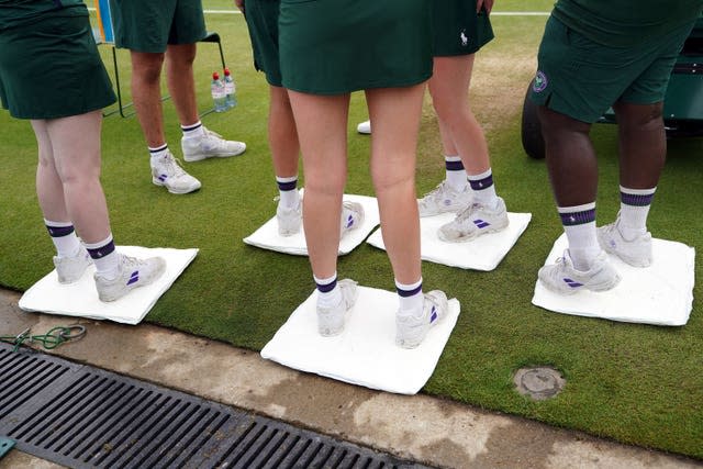 Ground staff attempt to dry the outside of a court on day six of Wimbledon