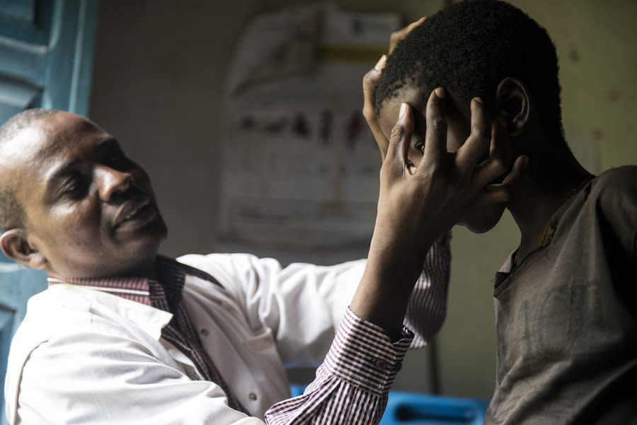 A Congolese doctor examines a nodule full of worms on a boy's head. (Photo: Neil Brandvold/DNDi)