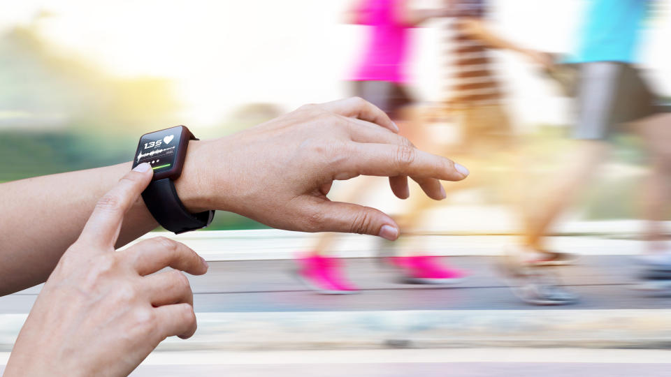 Woman checking up heart rate from smart watch on people running background