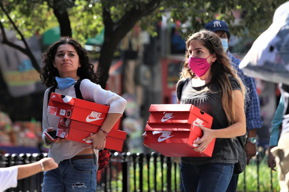 Dosw compradoras y cargan cajas con zapatos tenis nuevos durante el día de compras 