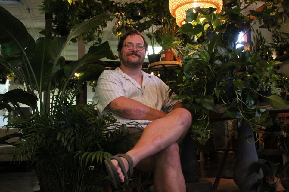 Flanked by house plants available for rent is Stuart Eastman, owner of The Conservatory at 21 W. First St. in downtown Monroe.