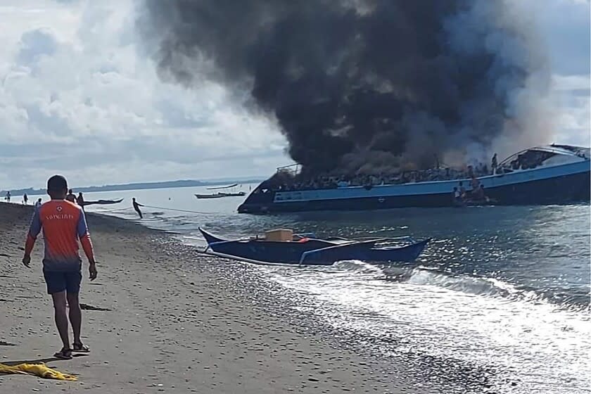 In this handout provided by the Philippine Coast Guard, smoke billows from ferry M/V Mercraft 2 as it's towed to an island off of the town of Real, Quezon province, Philippines on Monday, May 23, 2022. The passenger ship caught fire as it neared it's port destination in Real, killing several people on board. (Philippine Coast Guard via AP Photo)