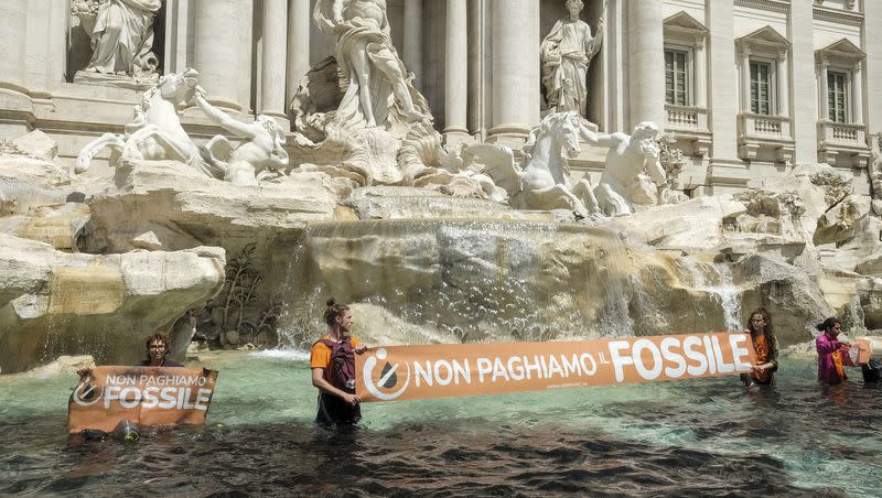 “Last Generation” environmentalists show a banner against the use of fossil fuels after vandalizing the water of the Trevi Fountain in Rome, Sunday, May 21, 2023. 