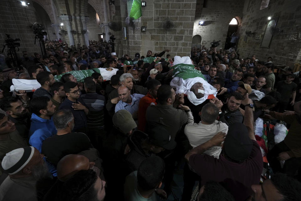 Mourners carry the bodies of Palestinians who were killed in Israeli airstrikes, during their funeral at the Omari mosque in Gaza City, Tuesday, May 9, 2023. The airstrikes killed three senior commanders of the militant Islamic Jihad group and 10 other people, including two of the commanders' wives, several of their children and others nearby. (AP Photo/Adel Hana)