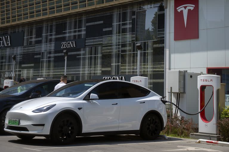 Un conductor sube a su automóvil en una estación de carga de vehículos eléctricos fuera de un concesionario Tesla en Pekín, el sábado 24 de junio de 2023.