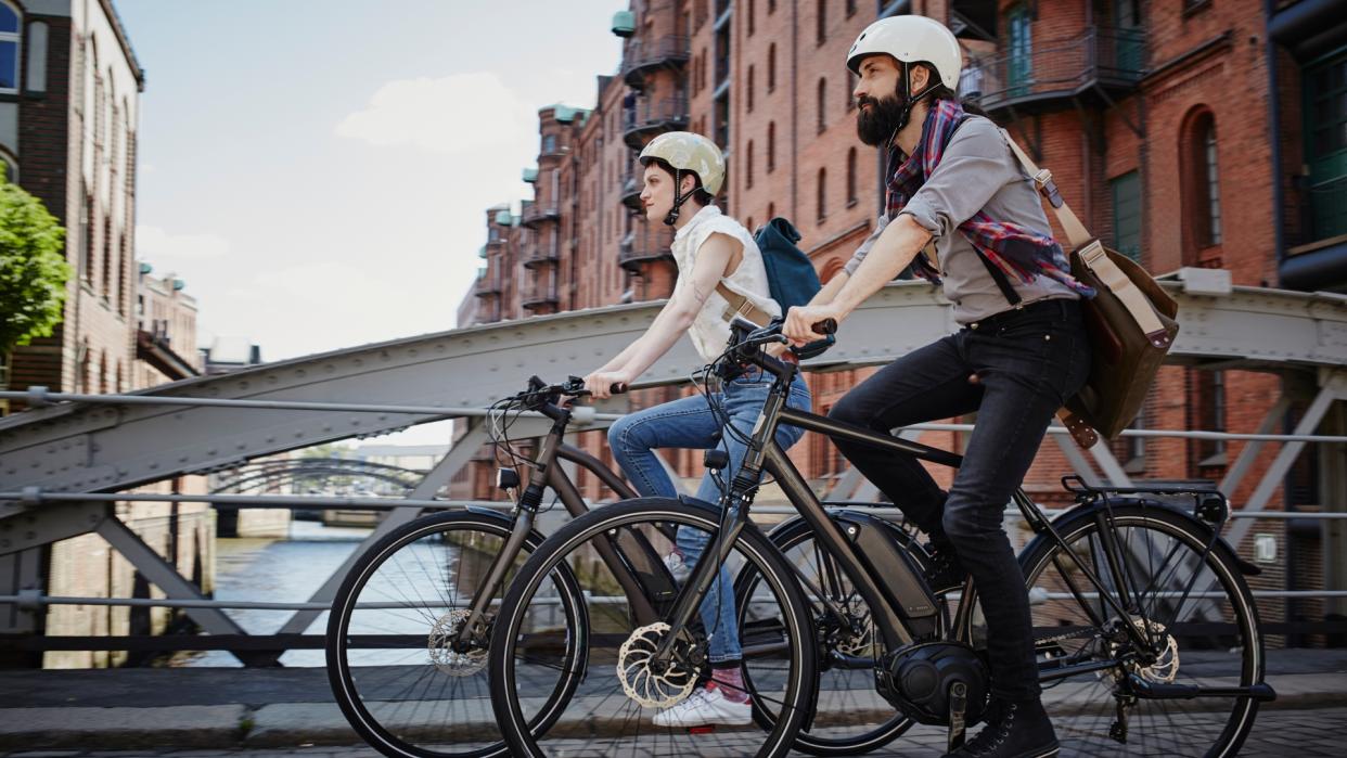  Images shows two people riding e-bikes in the city 