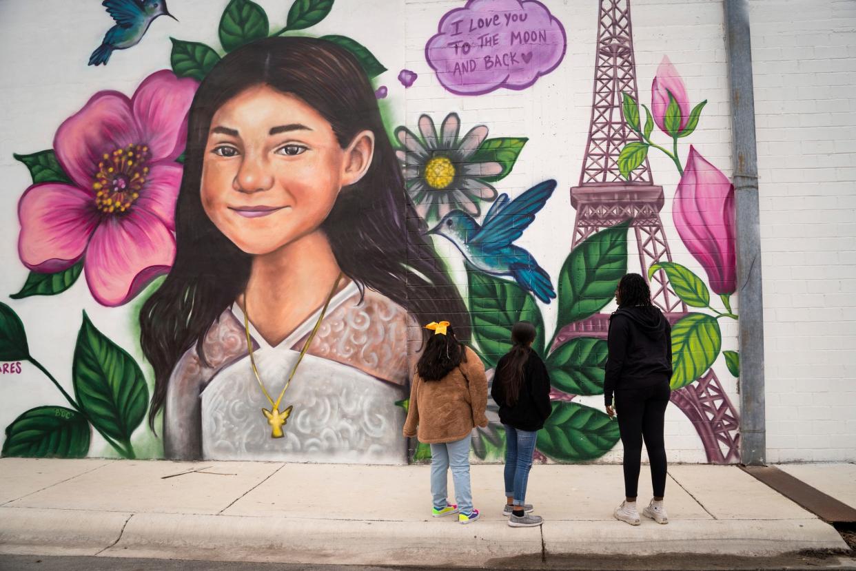 Camila Gonzalez, 7, left, and Caitlyne Gonzales, 10, both of Uvalde, Texas, show Zoe Touray, 18, of Pontiac, Michigan, a mural of Robb Elementary shooting victim Jacklyn "Jackie" Cazares, 9, on N. West Street and W. Roberts Lane in downtown Uvalde on Sunday, Nov. 20, 2022.