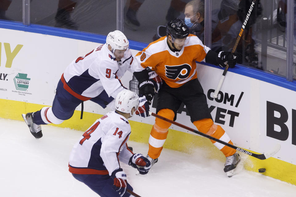 Washington Capitals defenseman Dmitry Orlov (9) and Philadelphia Flyers defenseman Robert Hagg (8) vie for the puck in the cornerduring the second period of an NHL hockey playoff game Thursday, Aug. 6, 2020, in Toronto. (Cole Burston/The Canadian Press via AP)