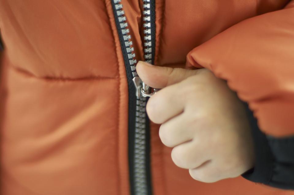 child pulling zip on orange jacket, close up