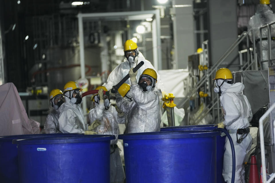Men in hazmat suits work inside a facility with equipment to remove radioactive materials from contaminated water at the Fukushima Daiichi nuclear power plant, run by Tokyo Electric Power Company Holdings (TEPCO), in Okuma town, northeastern Japan, Thursday, March 3, 2022. The government has announced plans to release the water after treatment and dilution to well below the legally releasable levels through a planned undersea tunnel at a site about 1 kilometer offshore. (AP Photo/Hiro Komae)