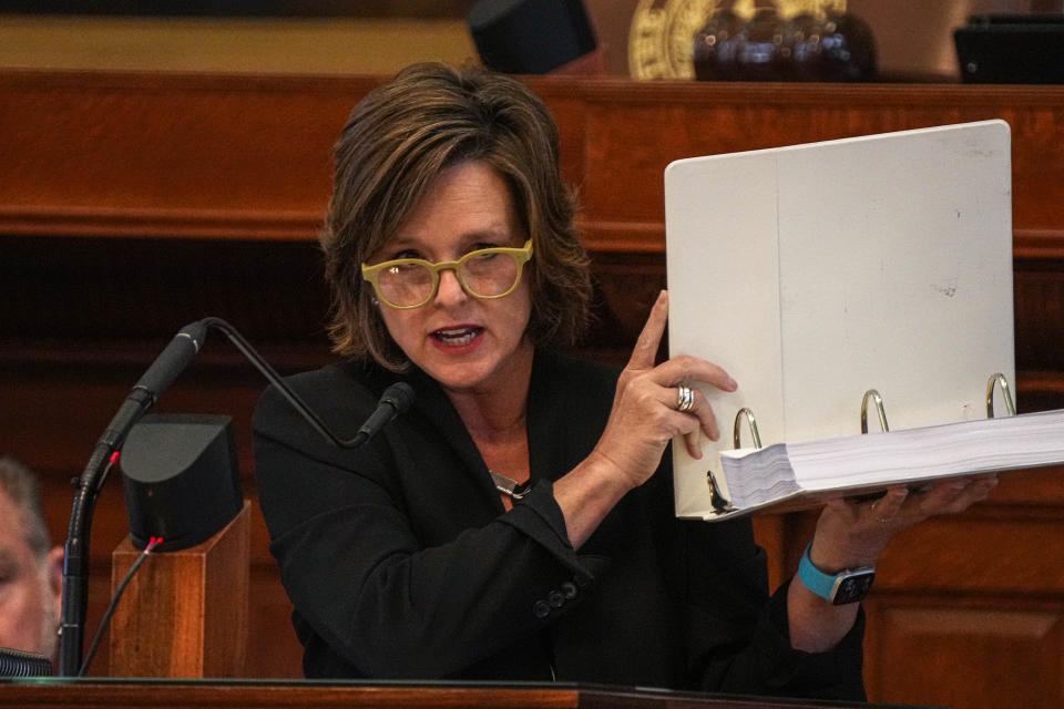 Rep. Ann Johnson, vice chair of the House General Investigating Committee, holds up a binder of evidence supporting the impeachment of Attorney General Ken Paxton on Saturday.