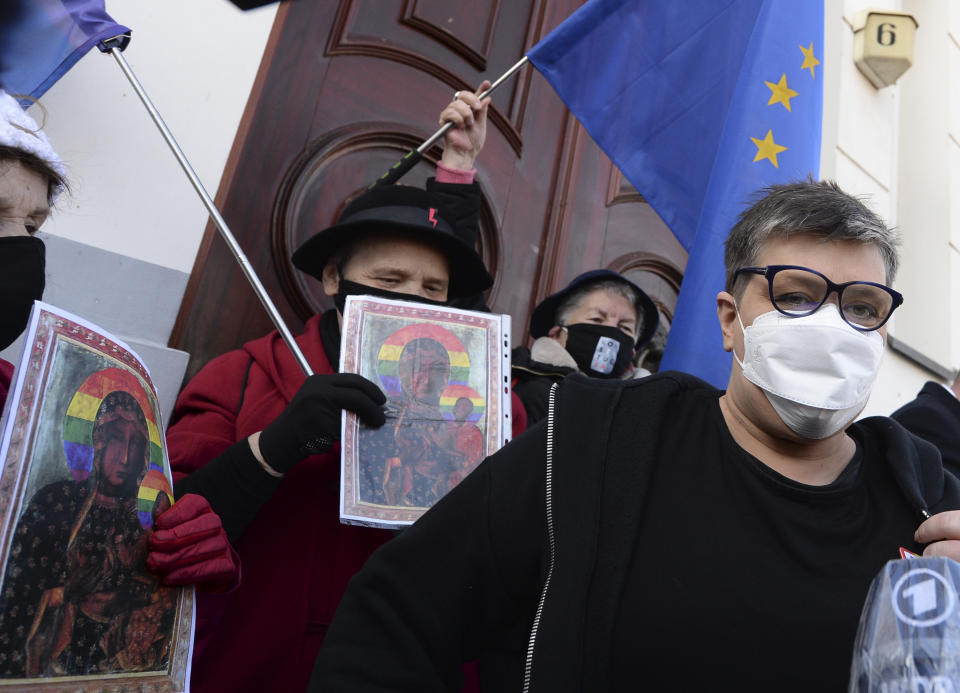 Polish activists Elzbieta Podlesna, right, is surround by supporters as she leaves the court after being acquitted of desecration by a court in Plock, Poland, Tuesday March 2, 2021. A Polish court has acquitted three activists who had been accused of desecration for adding the LGBT rainbow to images of a revered Roman Catholic icon. In posters that they put up in protest in their city of Plock, the activists used the rainbow in place of halos on a revered image of the Virgin Mary and baby Jesus. (AP Photo/Czarek Sokolowski)