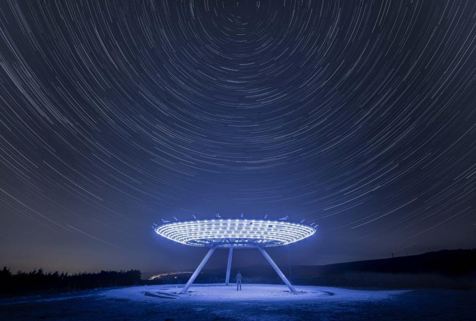 A spaceship-like sculpture under a time-lapse of stars