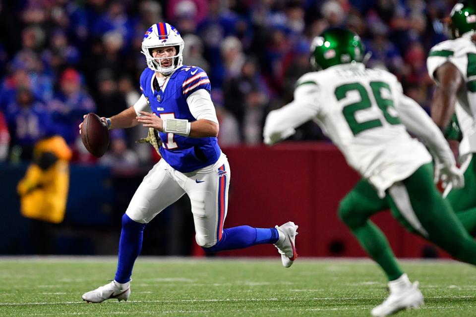 Buffalo Bills quarterback Josh Allen, left, rolls out looking to pass during the first half of an NFL football game against the New York Jets in Orchard Park, N.Y., Sunday, Nov. 19, 2023. (AP Photo/Adrian Kraus)