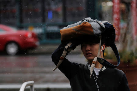 A man uses his backpack to shield himself during a rain shower in New York, U.S., March 1, 2017. REUTERS/Lucas Jackson