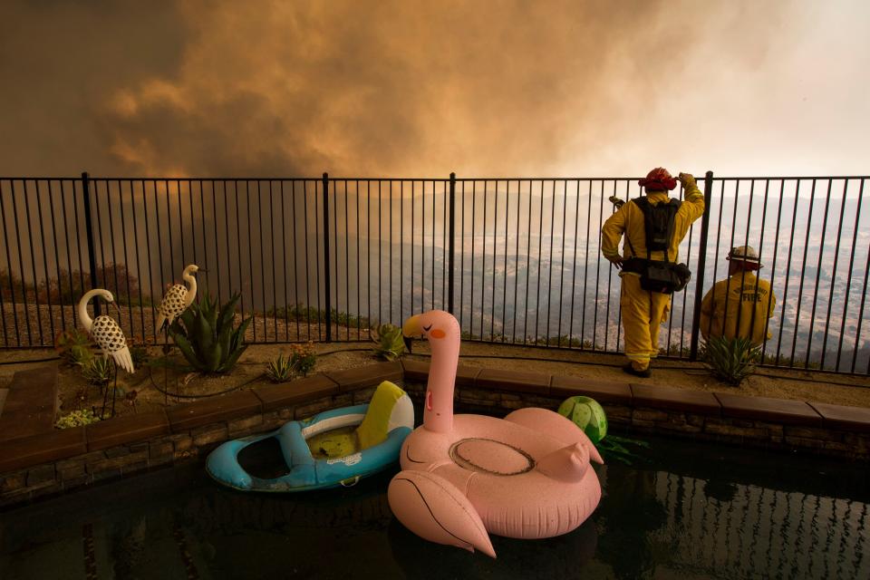 <p>Firefighters near a backyard pool monitor flames threatening homes during the Holy Fire in Lake Elsinore, Calif., Aug. 9, 2018. (Photo: David McNew/EPA-EFE/REX/Shutterstock) </p>