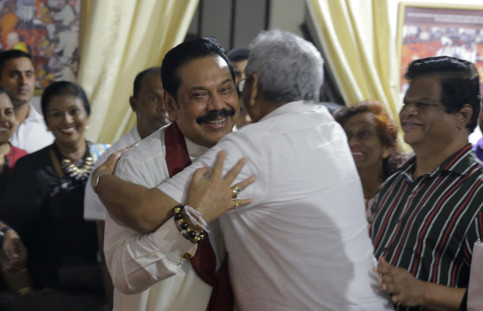 Newly appointed Sri Lankan Prime Minister Mahinda Rajapaksa, left, embraces his brother former defense secretary Gotabhaya Rajapaksa at a Buddhist temple in Colombo, Sri Lanka, Friday, Oct. 26, 2018. Sri Lankan President Maithripala Sirisena sacked the country's prime minister and his Cabinet and replaced him with a former strongman, creating what some observers said could be a constitutional crisis in the South Asian island nation. (AP Photo/Eranga Jayawardena)