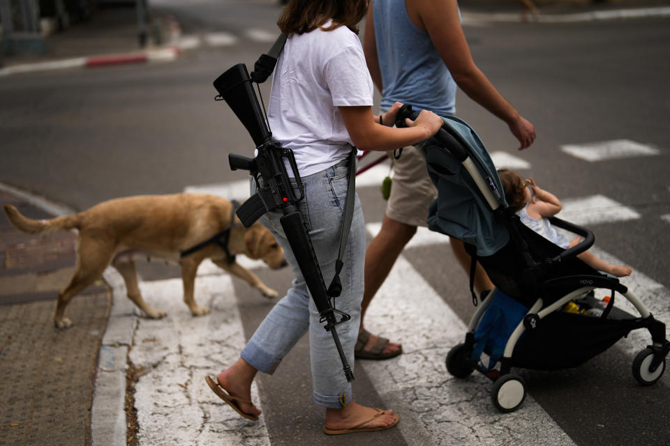 Yehudit, an off-duty Israeli soldier, pushes a trolley with her niece as they stroll in center Tel Aviv, Israel, Friday, Oct. 27, 2023. (AP Photo/Francisco Seco)