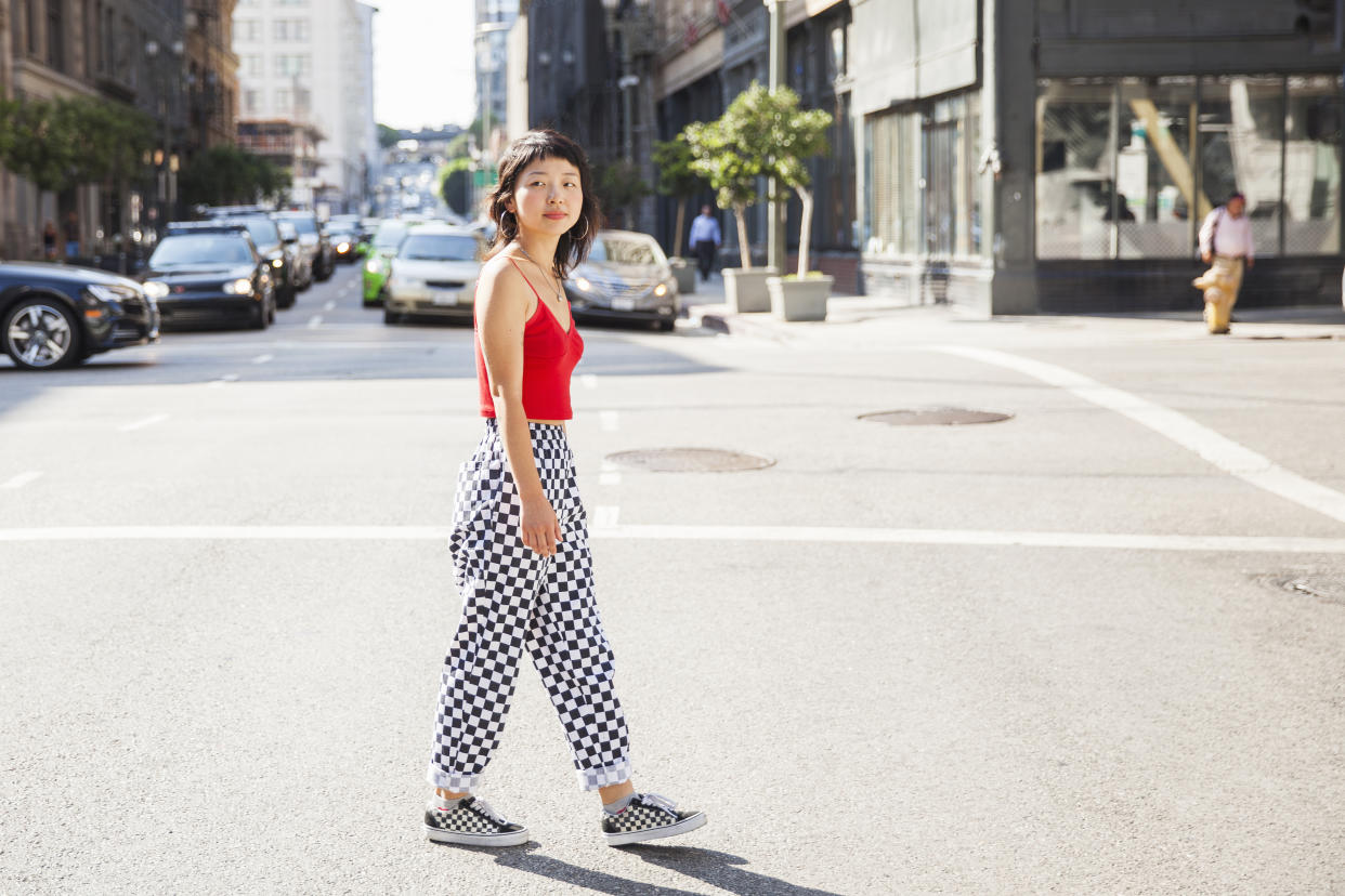 Hip, young Asian woman walking across a city street