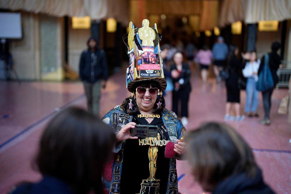 A woman in Oscars gear takes pictures on the red carpet ahead of the 96th Academy Awards, Thursday, March 7, 2024, in Los Angeles, California.